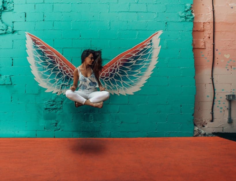 Good yoga habits can leave you free to practice without stress, leaving you floating like this woman in from of some angel wings painted on a wall