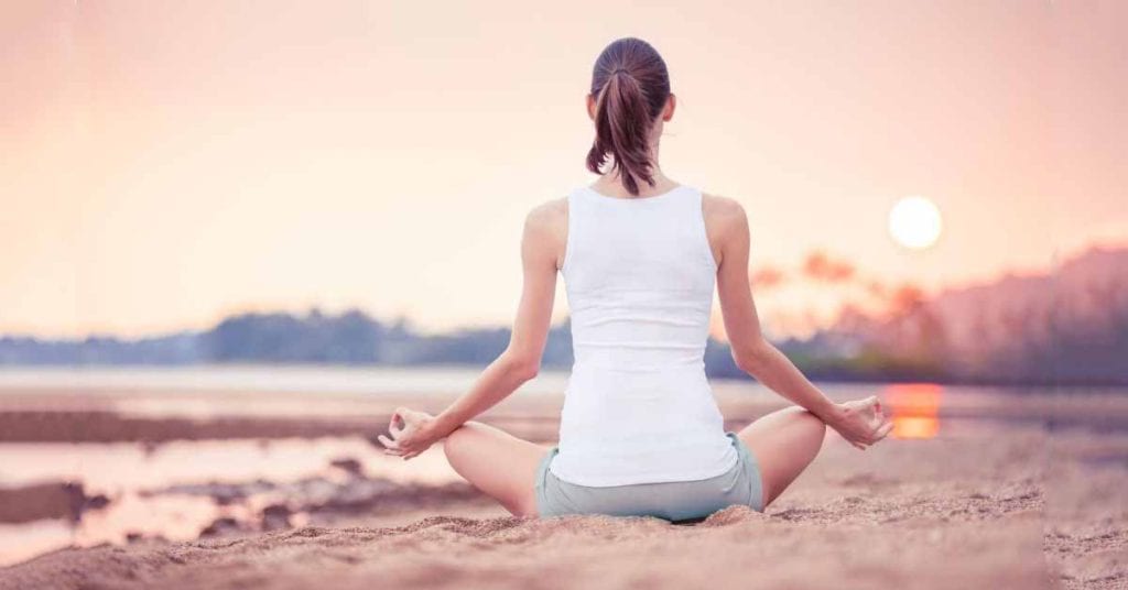 woman meditation on beach in sunset