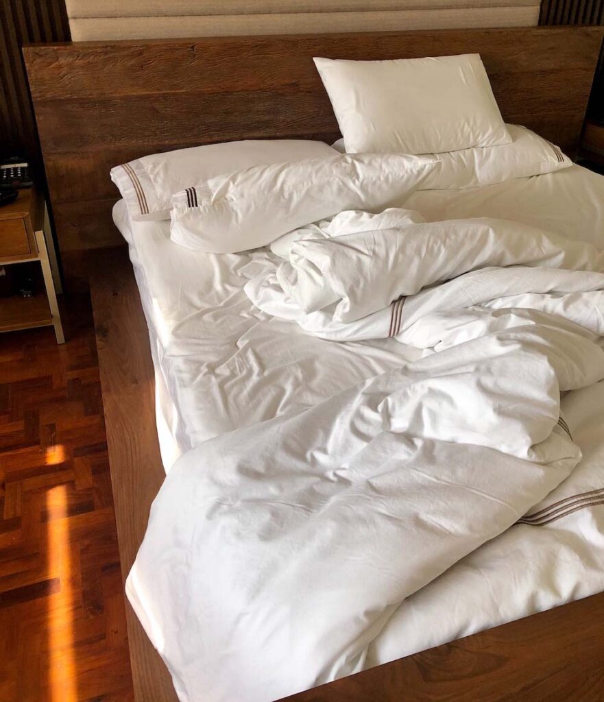unmade bed with white sheets left for a quick trip to pick up a Morning-after pill